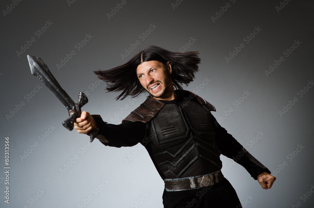 Angry knight with sword against dark background Angry knight with sword against dark background