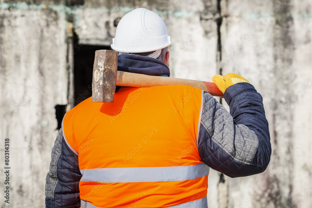 Worker with sledge hammer against the wall
