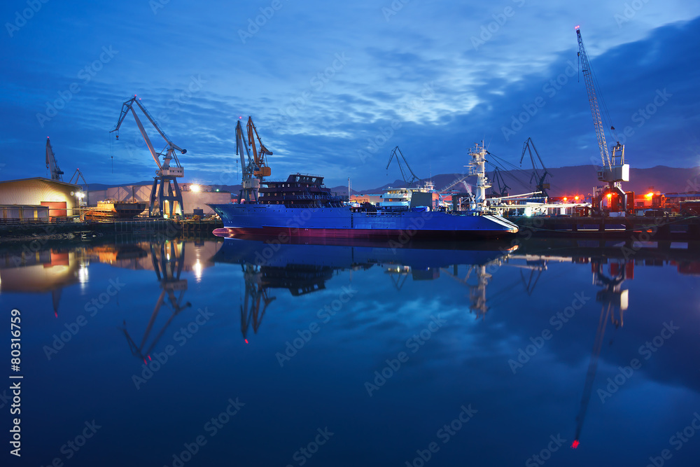 dock with cranes and ship at night