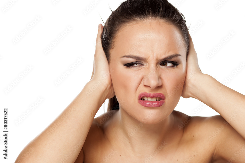 young woman closes her ears because of the noise