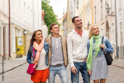 group of smiling friends walking in the city