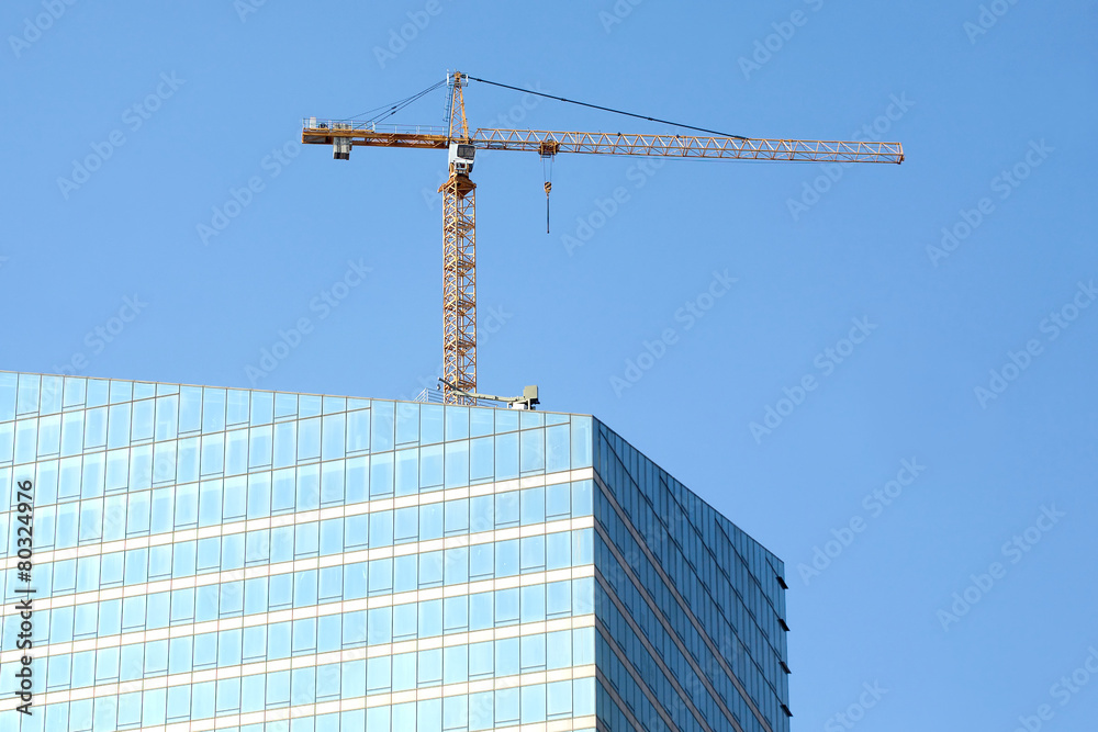 Yellow hoisting tower crane on top of construction skyscraper Yellow hoisting tower crane on top of construction skyscraper