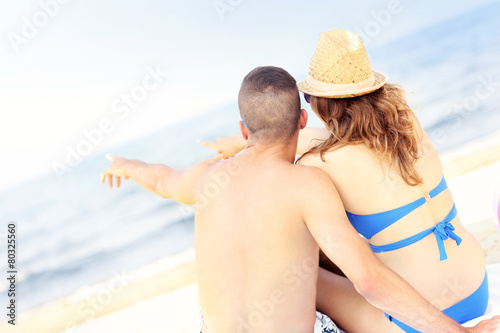 Happy couple pointing at something at the beach