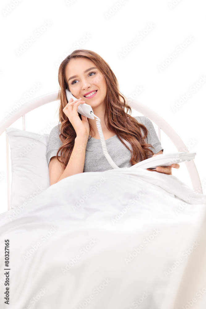 Young woman lying in bed and talking on phone Young woman lying in bed and talking on phone