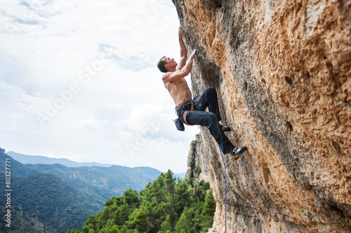 Young male rock climber on challenging route on cliff