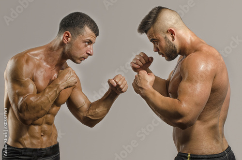 Two muscular men fighting, bodybuilders punching each other photo