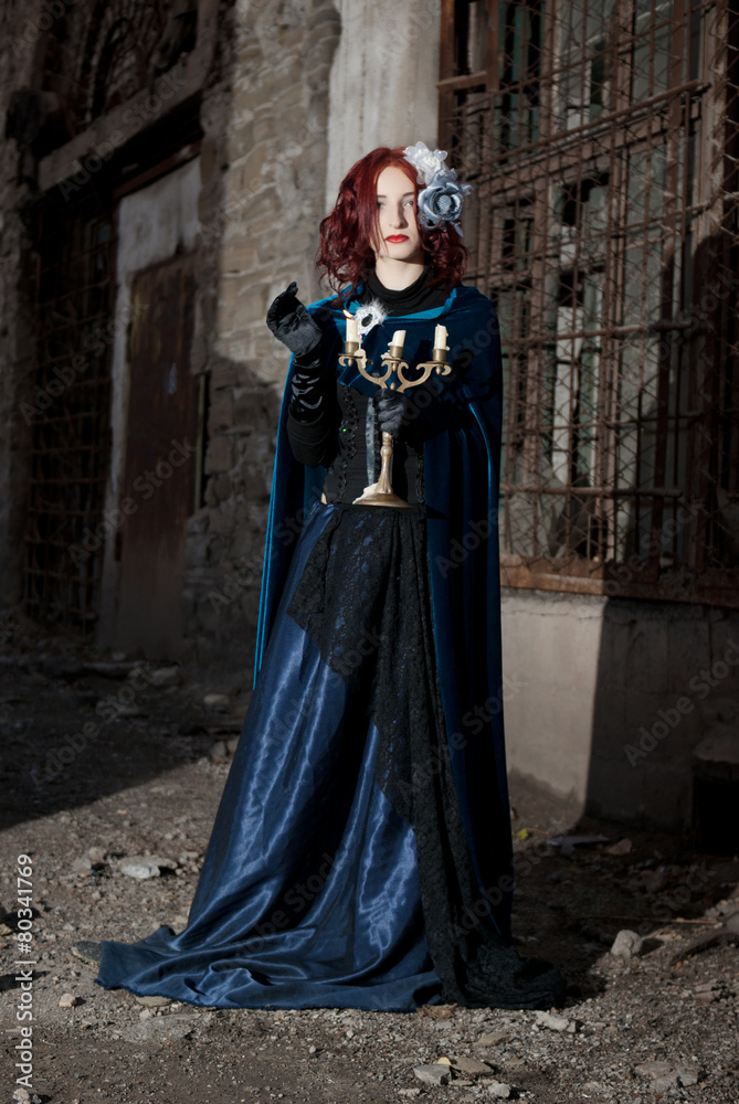 Gothic redhead woman walking with candle