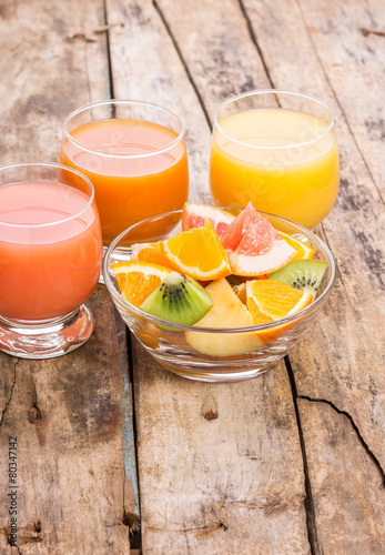 Fresh salad with fruits in glass bowl on wooden table. photo