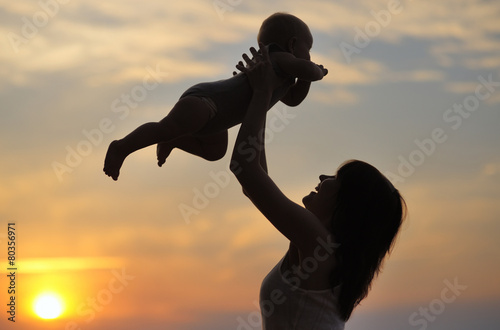 Woman with little baby as silhouette