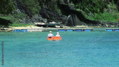 Old couple on pedal boat on the sea coming back to the beach