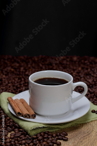 Coffee cup and saucer and coffee beans. Dark background.