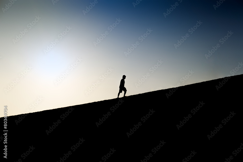 Fototapeta premium Silhouette of a man climbing a hill