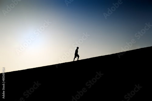 Silhouette of a man climbing a hill