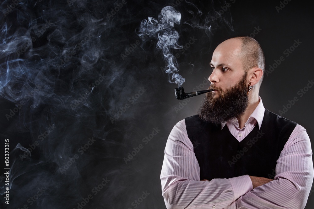 Bald bearded man smoking a pipe