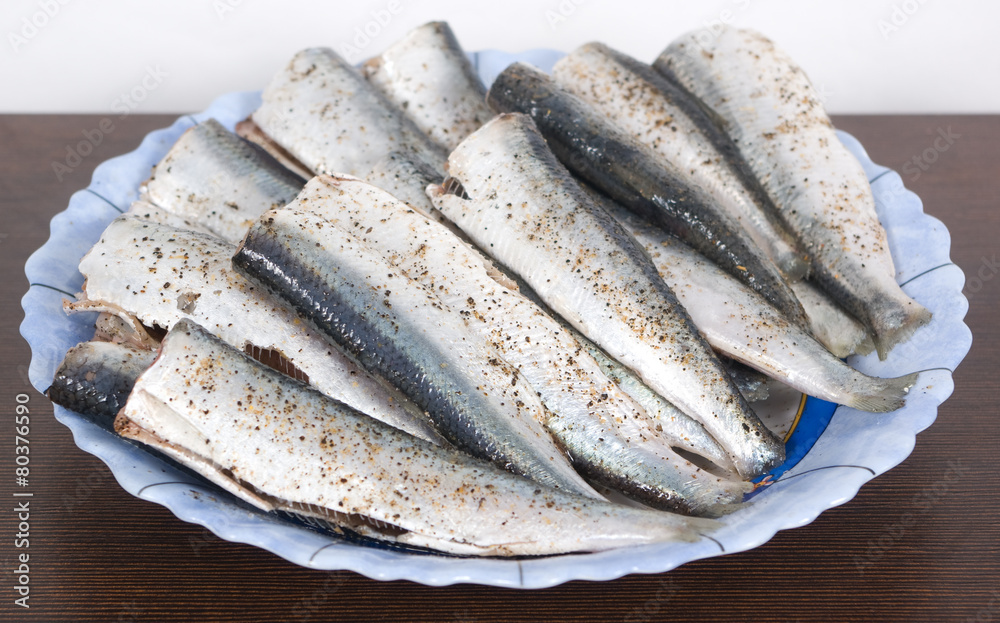 Sprats with salt and pepper ready for cooking on a plate Sprats with salt and pepper ready for cooking on a plate