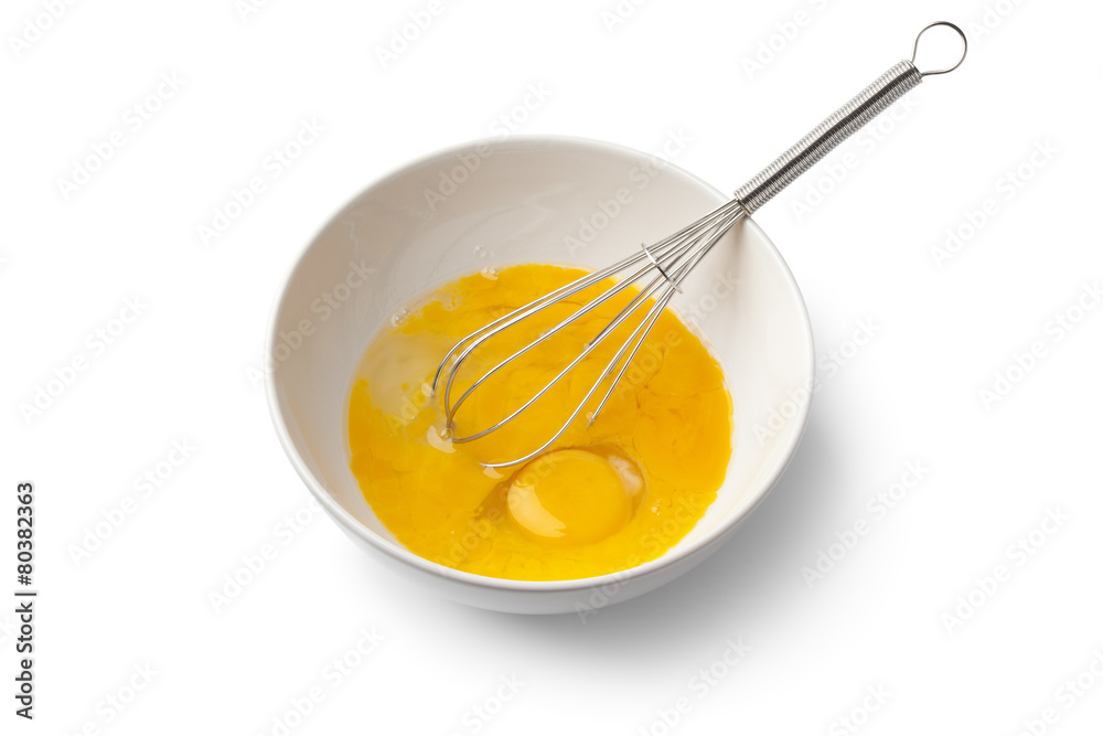 Beaten egg yolks in a bowl with whisk Beaten egg yolks in a bowl with whisk