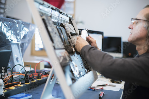 Computer Repair Shop. A man with a computer monitor, taking it apart to mend it. 