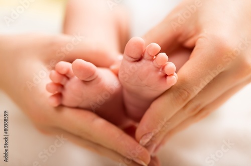Child. Baby feet in mother hands. Tiny Newborn Baby's feet on