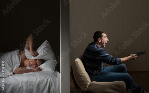 Man at night can't fall asleep because of the noisy neighbor