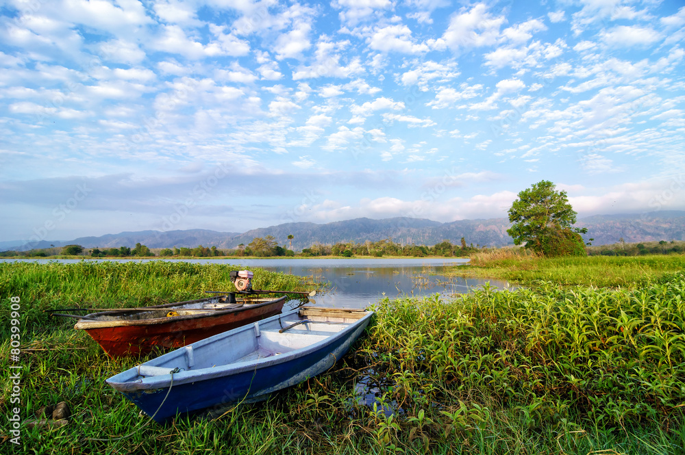 Two fishing boats by the lakeside during hot sunny day