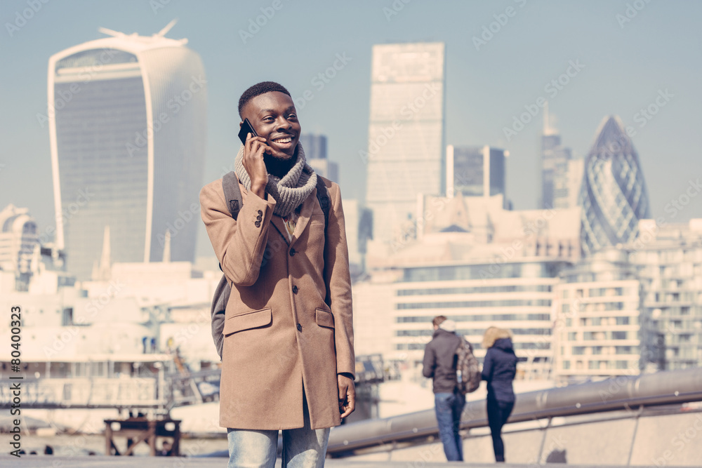 Naklejka premium Młody mężczyzna rozmawia przez telefon komórkowy z Londynu w tle