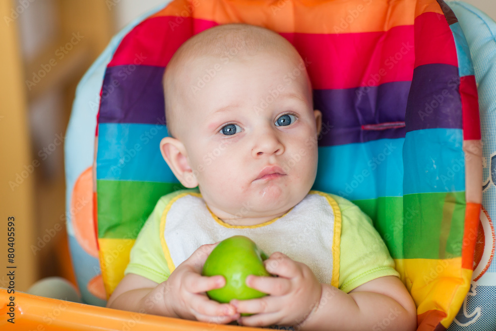 Adorable baby eating apple in high chair Adorable baby eating apple in high chair