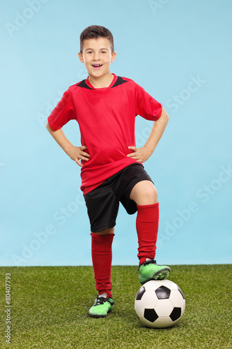 Junior in a soccer uniform standing over a soccer ball