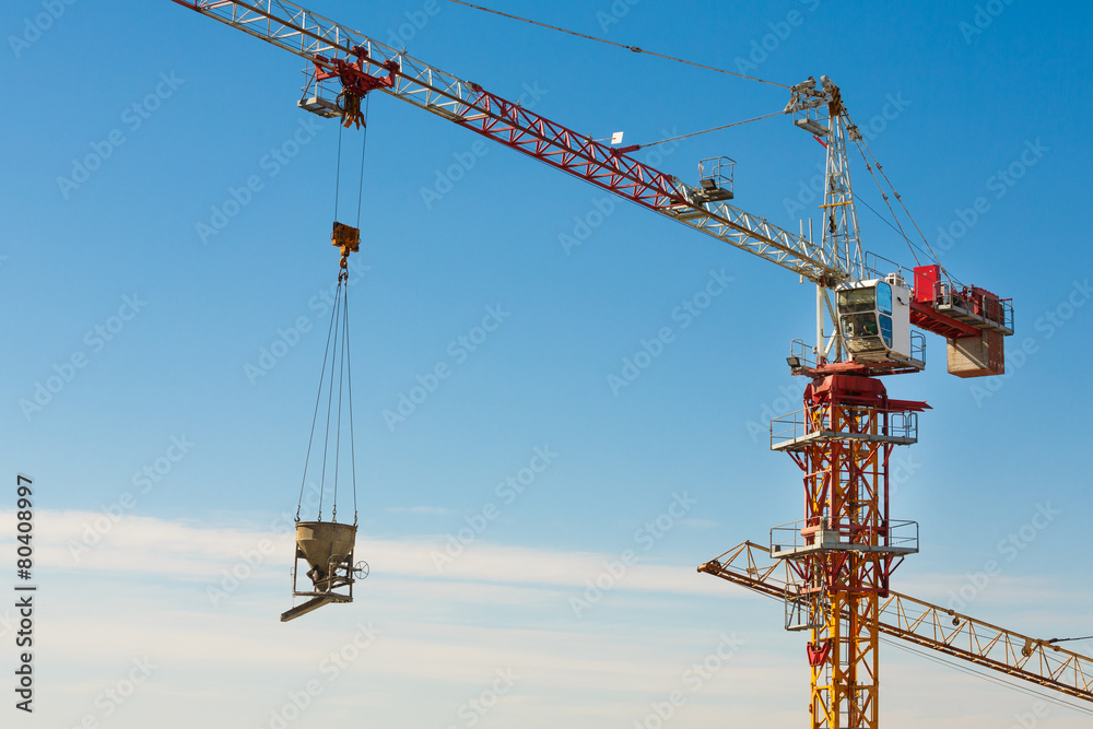 Tower crane lifting up a cement bucket at construction area