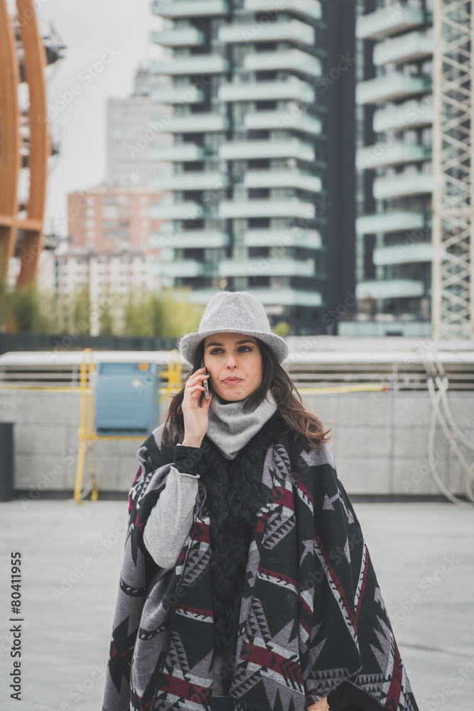 Fototapeta premium Beautiful young brunette talking on phone in the city streets