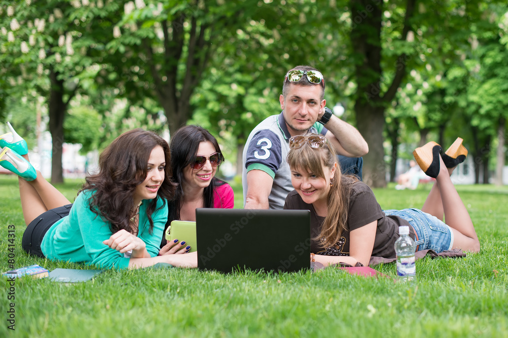 Group of Teenage Students at Park with Computer and Books Group of Teenage Students at Park with Computer and Books