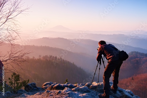 Professional photographer takes photos with camera on rock