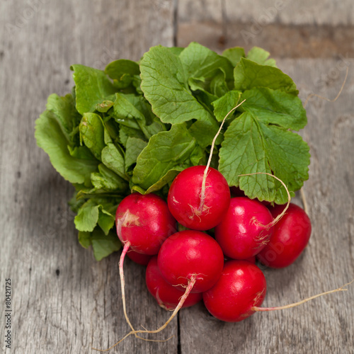 Fresh radishes on old wooden background. Selective focus.