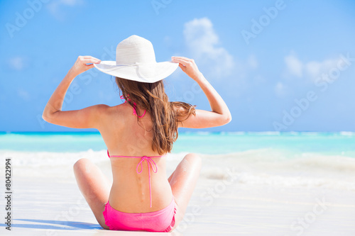 back view of long haired woman in bikini and wearing a hat on