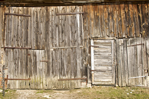 barn wall with doors, made of old wooden planks in early Spring