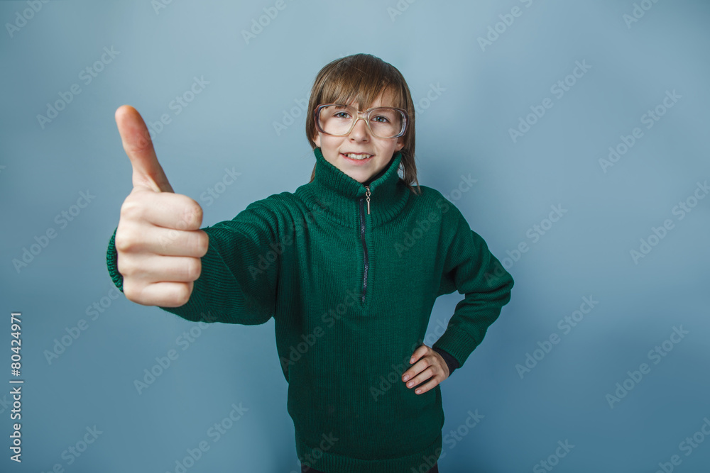 European-looking boy of ten years showing thumbs up on blue European-looking boy of ten years showing thumbs up on blue