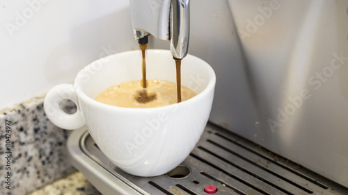 Pouring a coffee espresso on a machine in a white mug