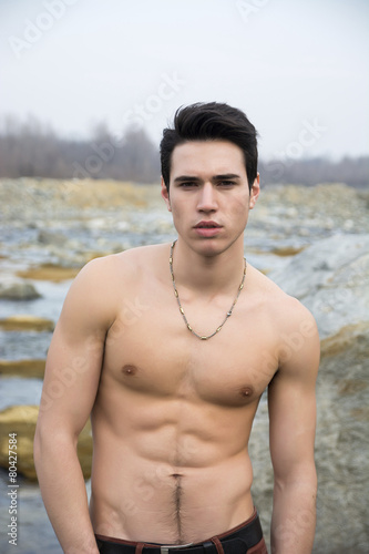Athletic shirtless young man outdoor at river or water stream