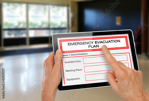 Hands with Computer Tablet and Emergency Evacuation Plan
