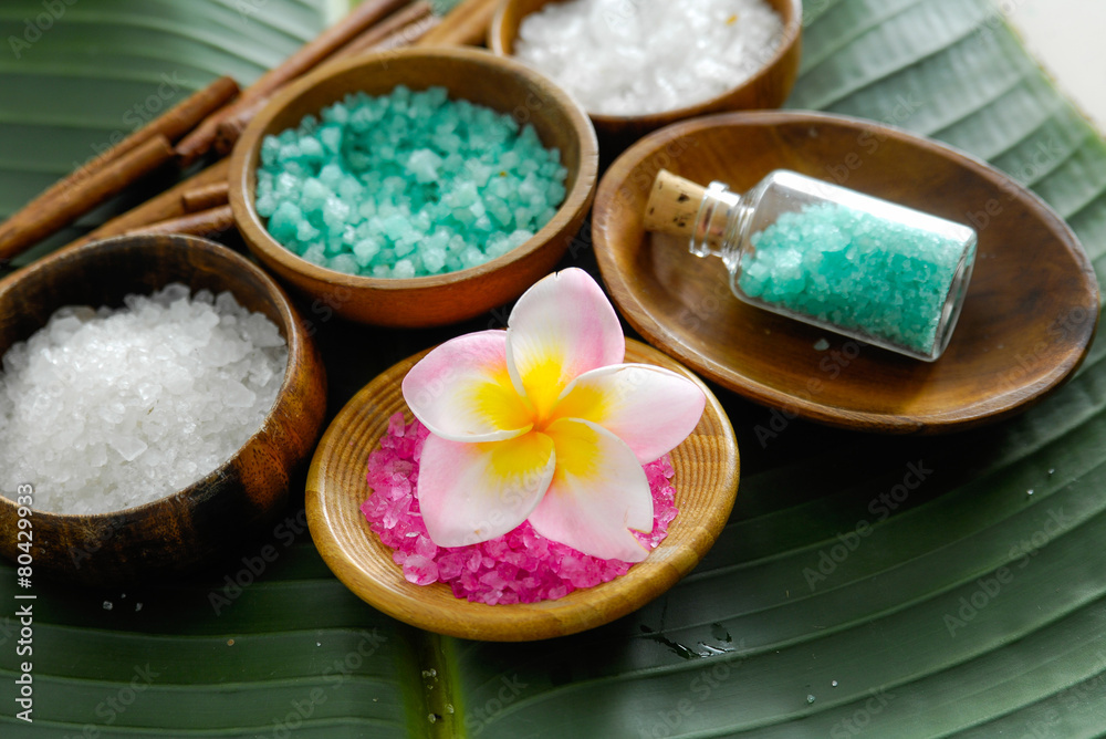 colorful salt , frangipani flower in wooden bowl with cinnamon on banana leaf 

