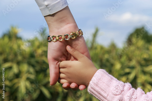 Mother and little girl s  hands in green garden