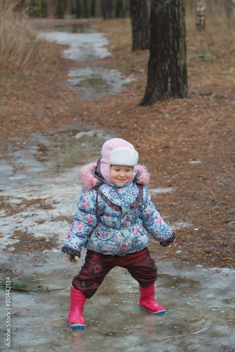 Fototapeta Naklejka Na Ścianę i Meble -  Two years old girl playing in icy puddle