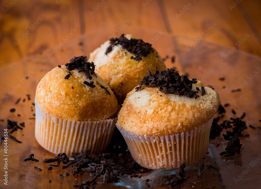 three chocolate chip muffins on wooden table three chocolate chip muffins on wooden table