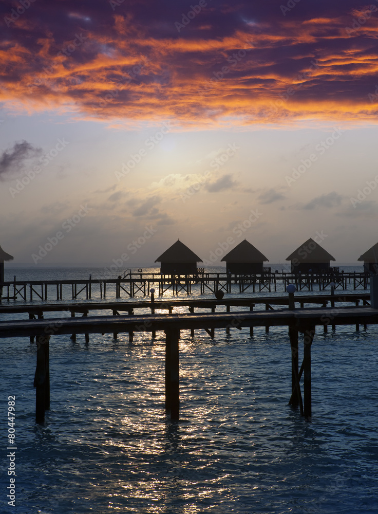 Silhouette of lodges in the sea at sunset. Maldives