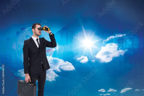 Businessman holding a briefcase while using binoculars