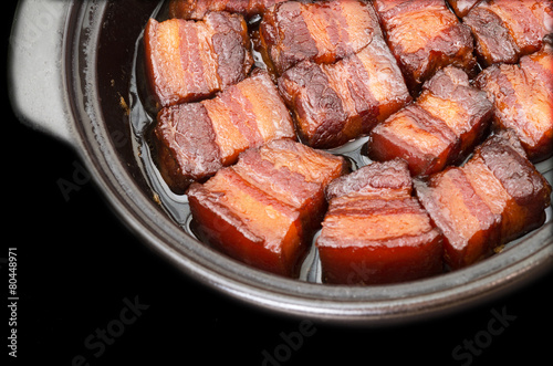 Vietnamese caramelized pork belly in clay pot on black backgroun photo