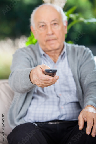 Elderly Man Using Remote Control While Sitting On Couch
