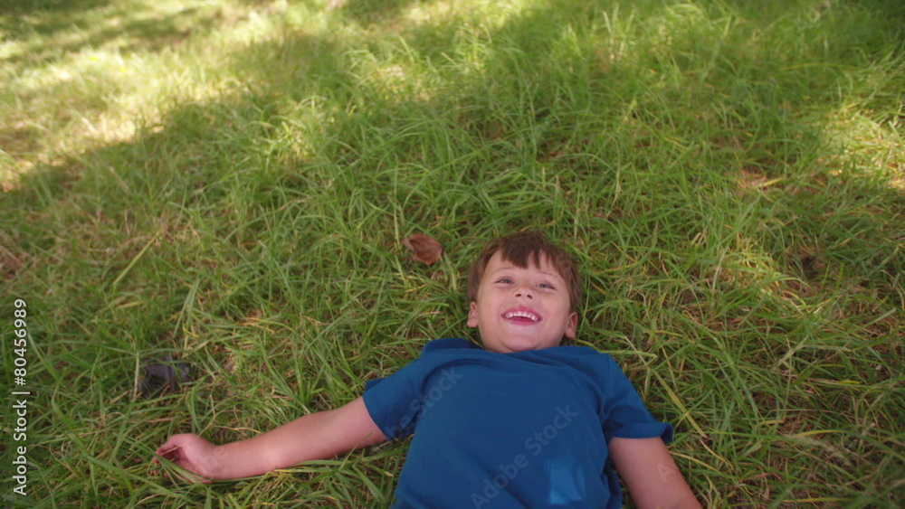Happy little boy lying in grassy park Happy little boy lying in grassy park