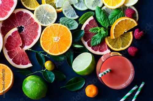 Fresh citrus slices and juice on black background top view photo