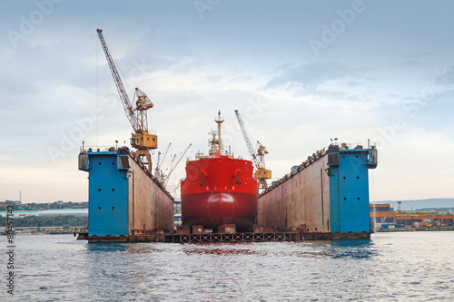 Floating blue dry dock with red tanker under repair © evannovostro