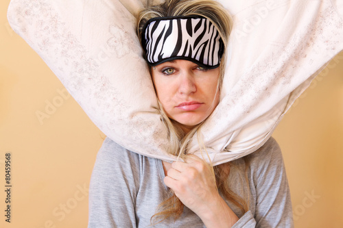 Sleepy young women with pillow and sleeping eye mask still on. photo